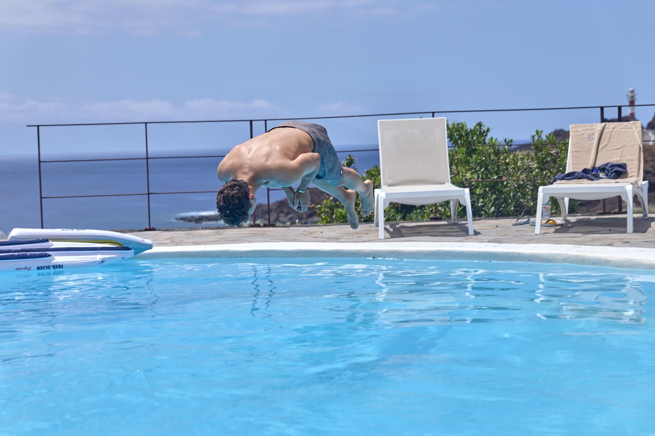 Salto a la piscina con el faro al fondo